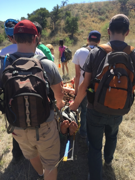 Wilderness medicine students carrying injured patient in stretcher